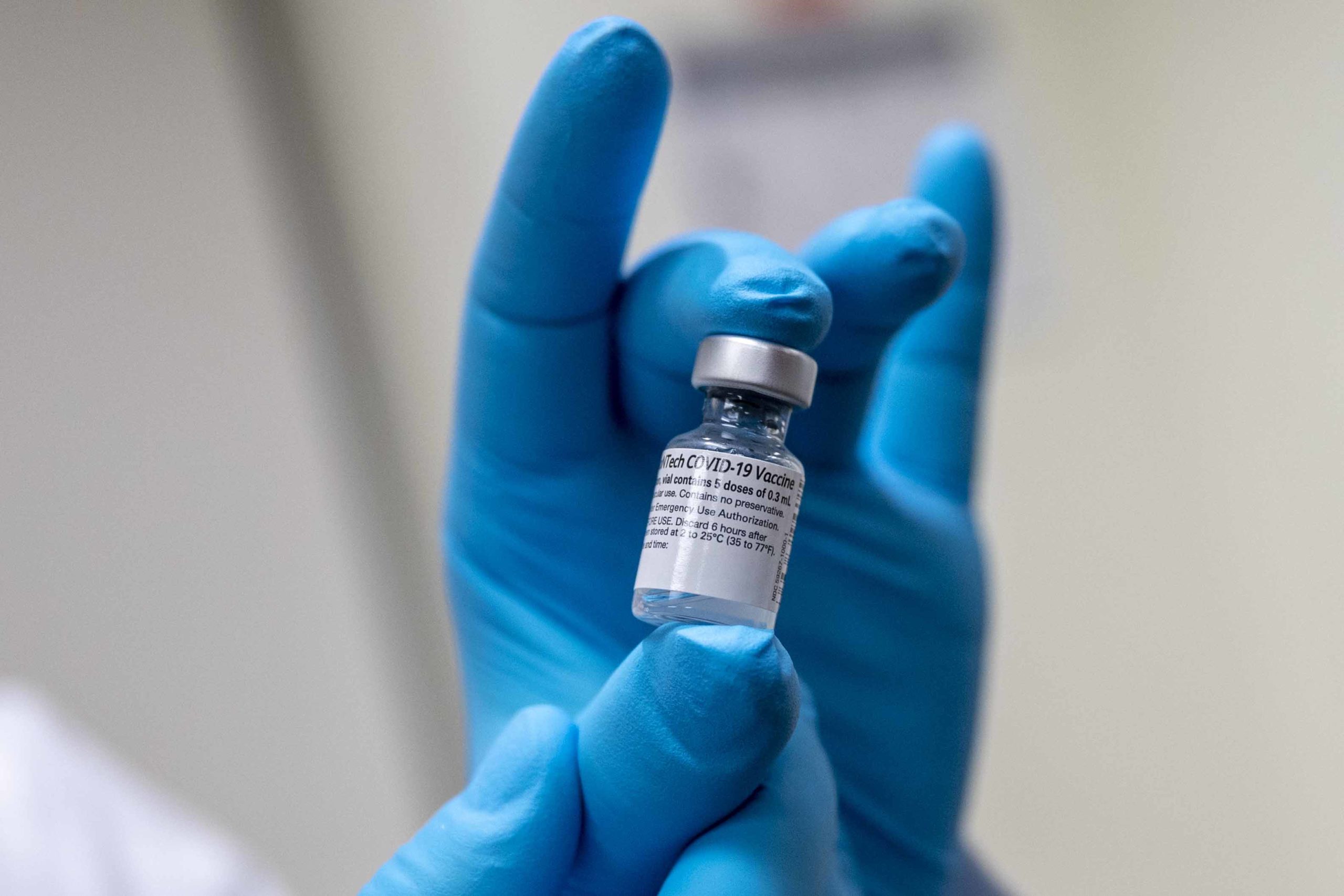 Army Spc. Angel Laureano holds a vial of the COVID-19 vaccine