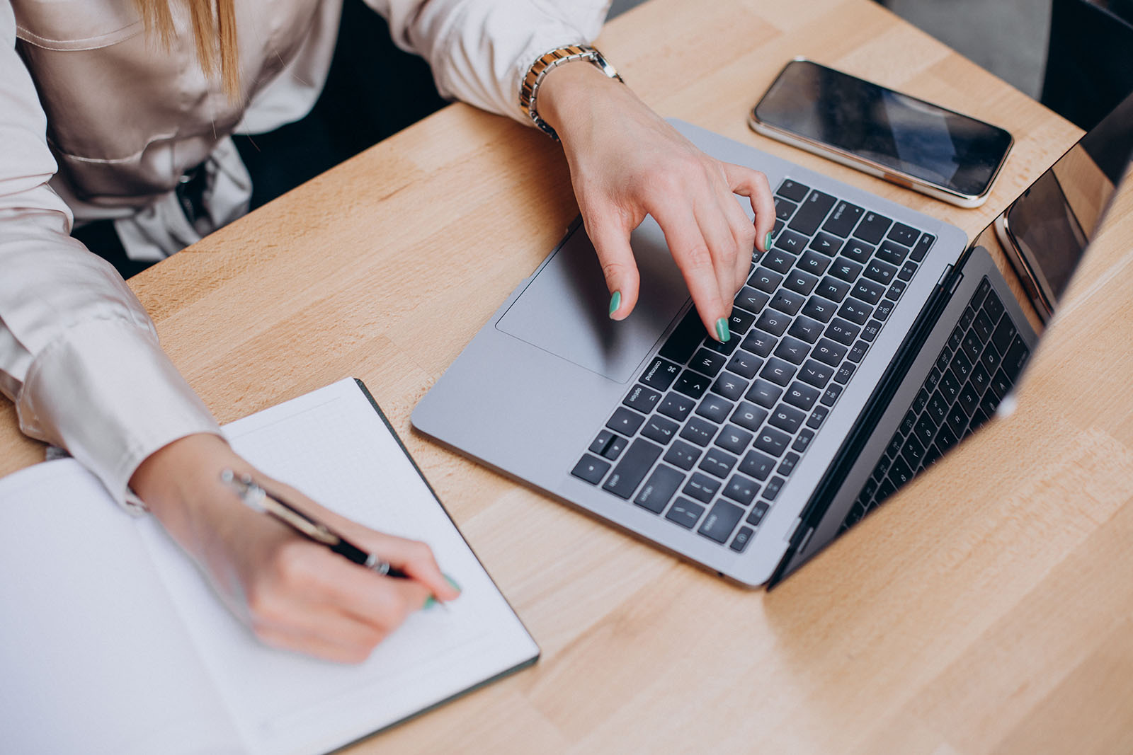 Female-hands-writing-notepad-working-computer