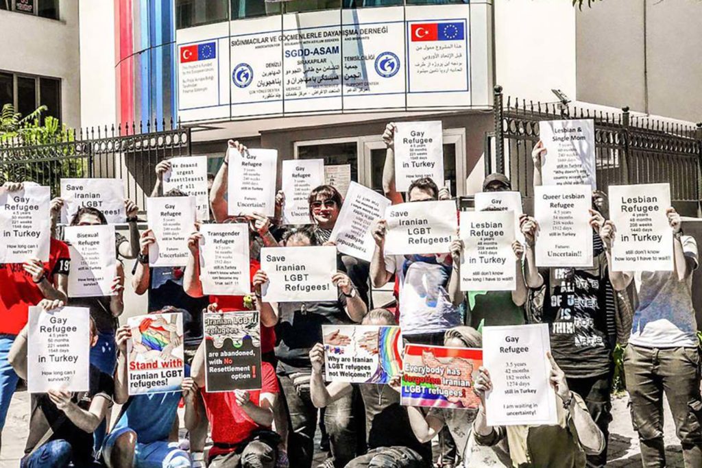 Protesters holding up signs in support of Iranian LGBT refugees