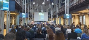 Audience seated in chairs listening to a panel of four people peak