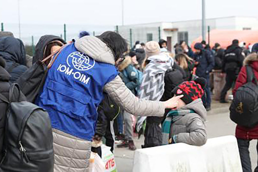 IOM Ukraine volunteer helping to direct two children at the border