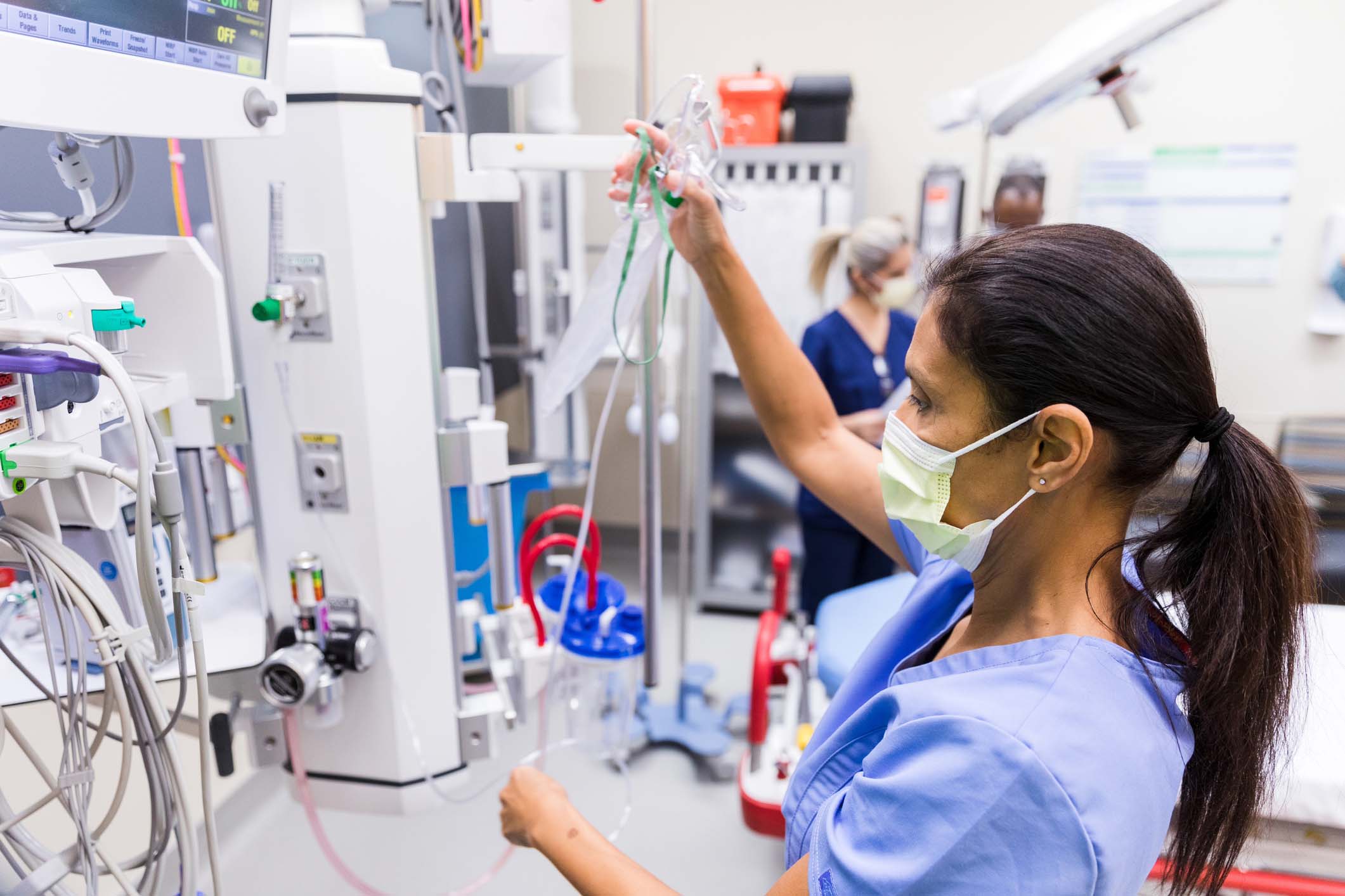 Female nurse with mask checks medical equipment in ER