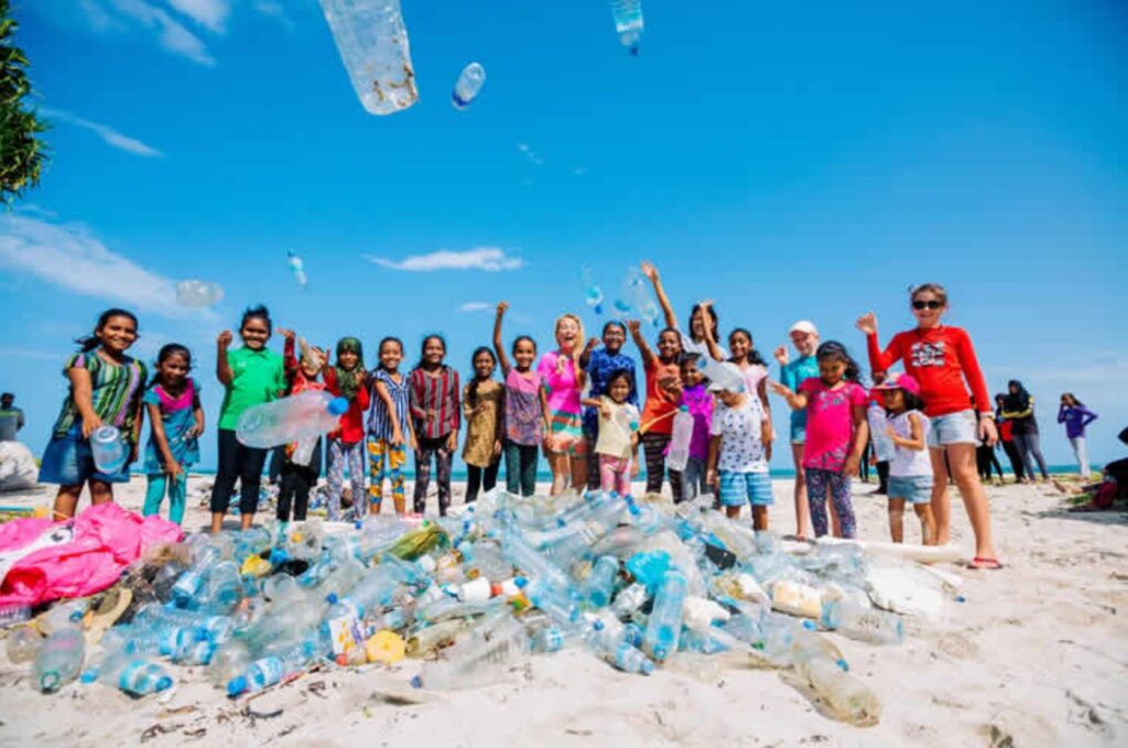 a group of children on the beach, with garbage and plastic piled in front of them