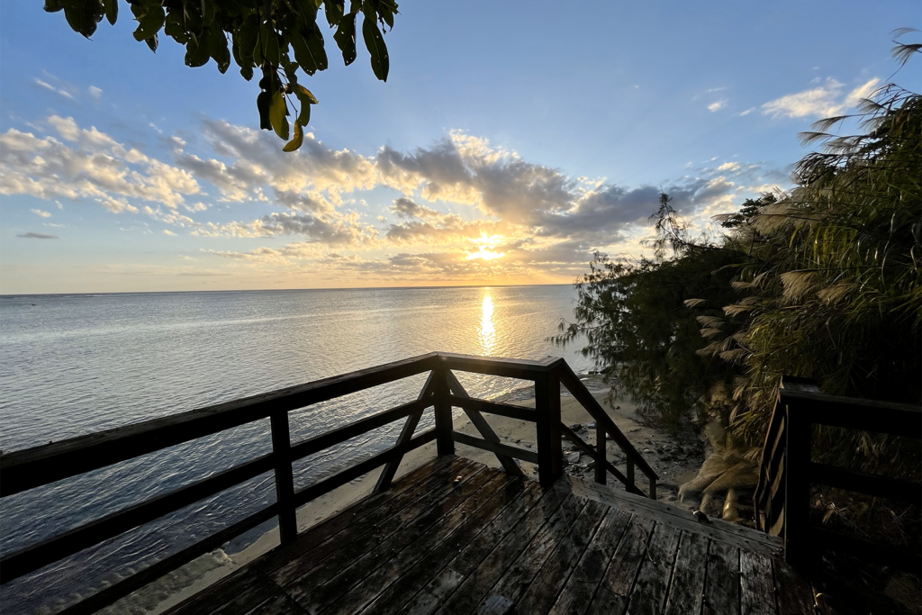 Photo of sunset over the water with a wooden staircase in the foreground