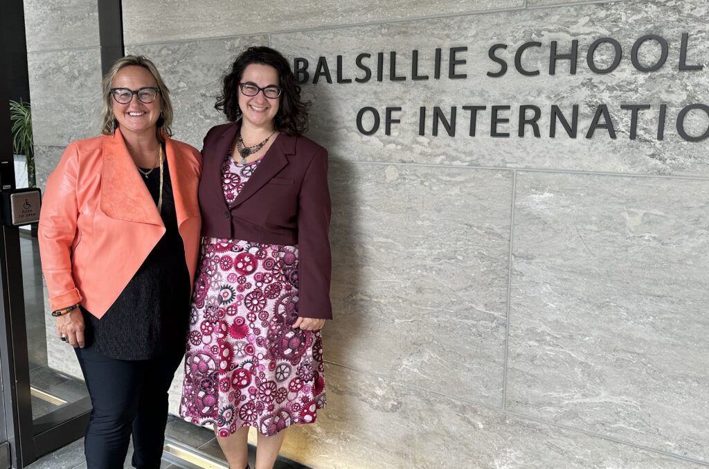 Jenna Hennebry and Allison Petrozziello stand in front of the Balsillie School sign