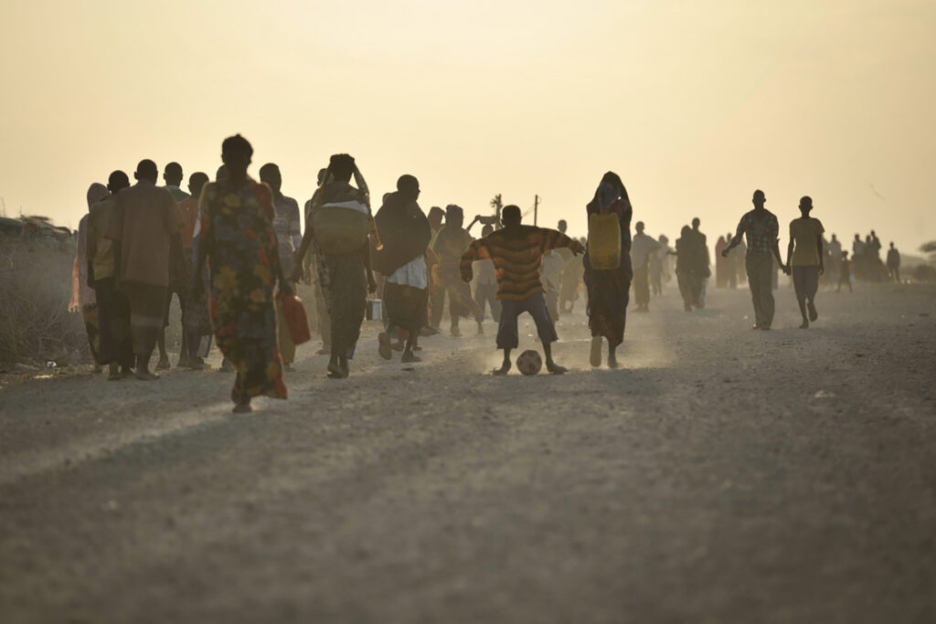 Silouette of a crowd of people walking on a dusty road at twilight