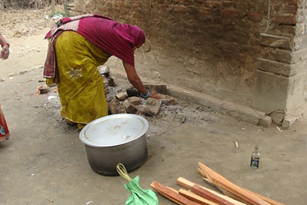 Woman bending down touching ashes in a fire pit.