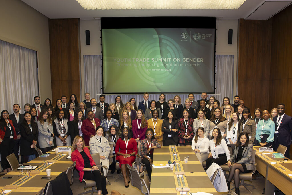 Group of people posing in front of a screen that says Youth Trade Summit on Gender