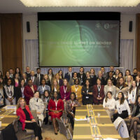 Group of people posing in front of a screen that says Youth Trade Summit on Gender