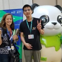 PhD student Tamara Lorincz stands with a student and a large panda statue