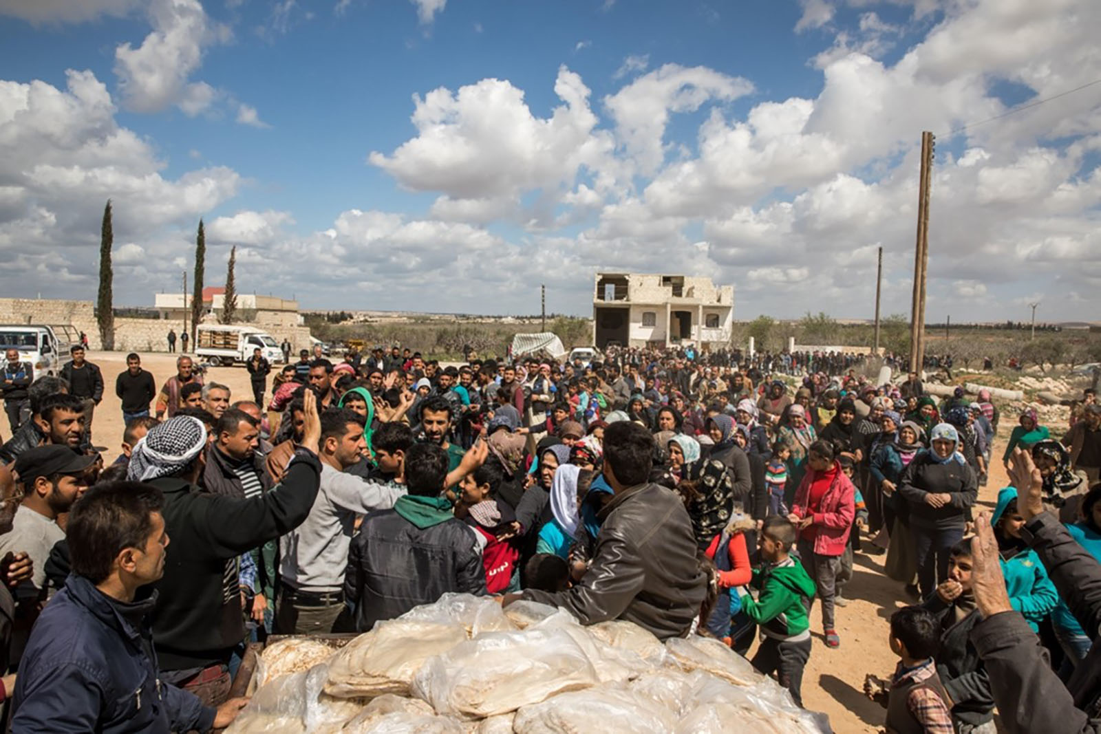 A crowd gathering around a food distribution wagon.