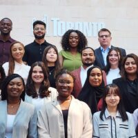 Group of 16 Fellows standing on stairs in front of the City of Toronto logo.