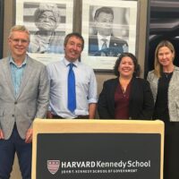 Photo of CIGI-Harvard-BSIA representatives standing behind a podium that reads "Harvard Kennedy School"