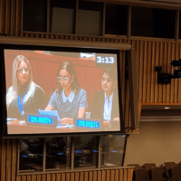 A screen projector showing three people in a conference.