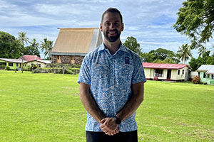 Isti Kery standing in front of houses and a green field.